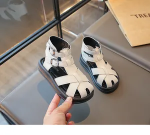 Detalle de sandalias romanas blancas para niños con hebillas y suelas negras gruesas