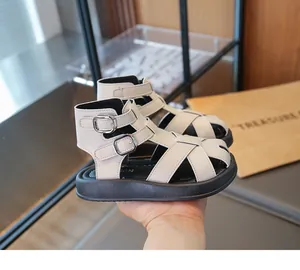 Vista detallada de sandalias romanas beige para niños con hebillas dobles modernas