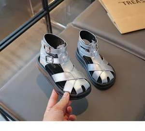Detalle de sandalias romanas plateadas para niños con correas de hebilla.