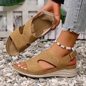 Close-up van kaki zomerse wedge sandalen met verfijnd opengewerkt patroon en klittenband.