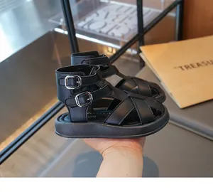 Vista de detalle de sandalias romanas negras para niños con elegantes hebillas plateadas.
