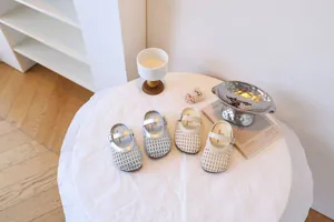 Vue détaillée de sandales d'été tressées pour filles en argent et blanc cassé sur une table
