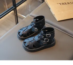 Vista lateral detallada de sandalias romanas negras para niños con hebilla doble en tobillo