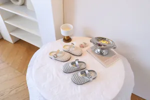 Détail de sandales tressées pour filles avec bride à boucle en argent et crème
