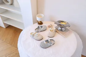 Détail de sandales d'été tissées pour filles en crème et argent sur une table décorée