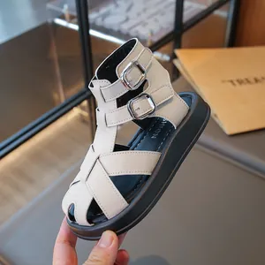 Elegantes sandalias romanas blancas para niños con suela de plataforma negra y hebillas plata.