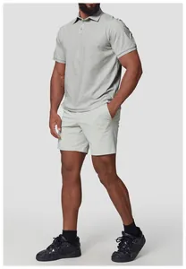 Model trägt ein hellgraues Herren-Quick-Dry-Polohemd und passende Shorts für einen Golf-Look.