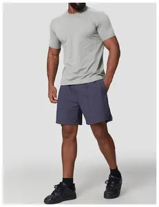 Full body view of a man wearing a grey quick-dry crew neck T-shirt and navy shorts.