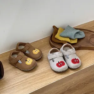 Vista detallada de zapatos Birkenstock para bebé con bordado de manzana en marrón y gris