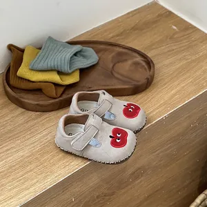 Primer plano de zapatos para bebé grises con bordado de manzana y suela blanda flexible