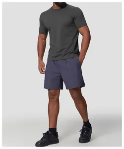 Man wearing a dark grey quick-dry performance T-shirt and athletic shorts against a grey background