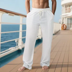 Vue complète d'un pantalon de plage blanc effet lin porté sur le pont d'un navire.