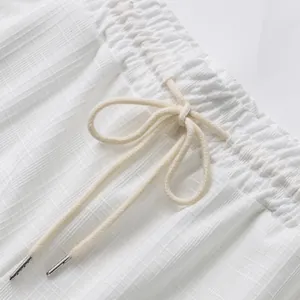 Détail de la taille élastique avec cordon de serrage pour pantalon d'été blanc à carreaux.