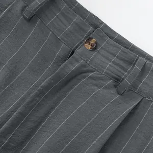 Detailed close-up showing grey pinstriped linen trousers waistband and brown button