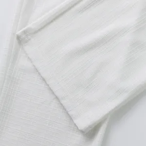 Gros plan détaillé du tissu texturé à carreaux façon lin d'un pantalon d'été blanc homme