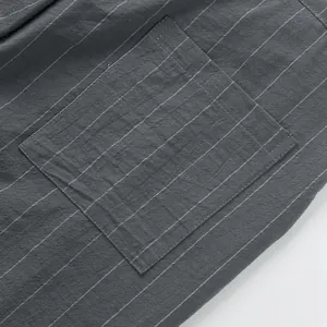 Close-up of square pocket and white vertical stripes on grey linen trousers texture.