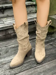Détail de bottes western en daim kaki souple avec bout pointu et talon bloc épais