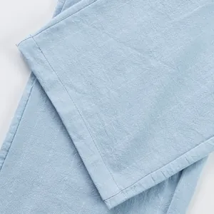 Detailed close-up showing the high-quality breathable linen fabric texture of light blue trousers