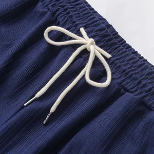 Gros plan d'un pantalon décontracté pour hommes avec cordon blanc et tissu bleu texturé.