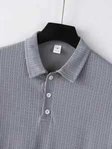Detail view of grey knitted polo shirt with check pattern and button-down collar