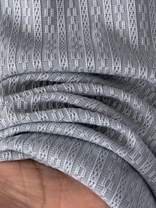 Detailed close-up view of light blue knitted polo shirt fabric featuring a small grid pattern