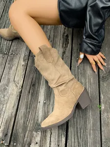 Bottes de cowboy en daim beige à bout pointu et talon bloc sur terrasse en bois