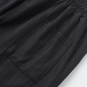 Vue détaillée d'un pantalon noir texturé avec poche arrière et taille élastique.
