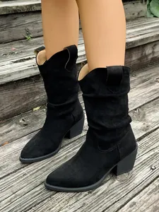 Gros plan de bottes western en daim noir avec bout pointu et talon épais et souple