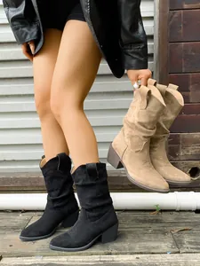 Gros plan de bottes de cowboy plissées en daim en noir et beige