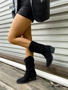 Détail de bottes western noires en daim plissées avec bout pointu et talon épais