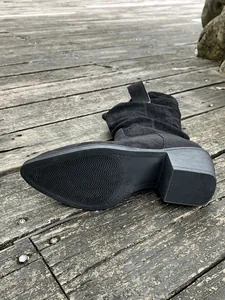 Détail d'une botte western noire avec semelle antidérapante et talon épais.