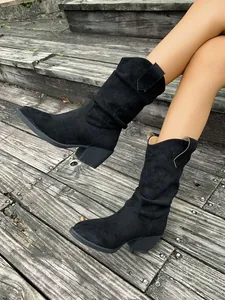 Détail de bottes western noires plissées avec bout pointu et talon épais élégant.