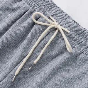 Gros plan sur la taille et le cordon blanc d'un pantalon décontracté gris à carreaux
