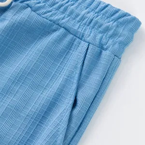 Gros plan d'un pantalon pour homme bleu clair montrant le tissu quadrillé et la poche