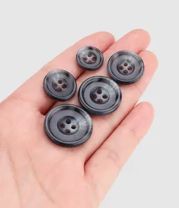 Macro view of five dark marble texture urea buttons with durable 4-hole design on hand