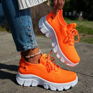 Detalle de zapatillas transpirables de tejido fly-woven naranja neón con suelas blancas gruesas