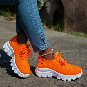 Primer plano de zapatillas de running de punto naranja vibrante para mujer al aire libre.