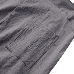 Détail rapproché de la texture du lin gris et des coutures de poche d'un pantalon homme