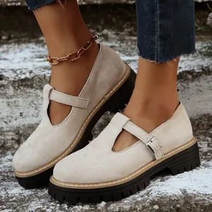 Primer plano de zapatos de plataforma beige retro con hebilla en T en una escalera exterior.