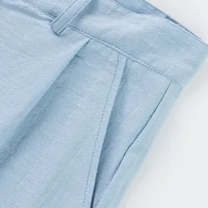 Close-up of light blue linen trousers showing waist belt loops and pocket detail