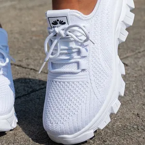 Primer plano de zapatillas blancas de punto transpirable para mujer con suela de goma