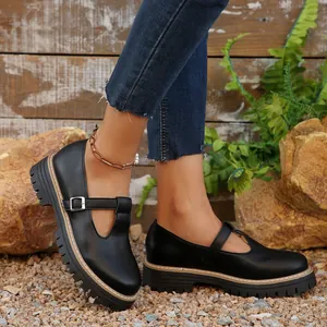 Primer plano de zapatos Mary Jane negros retro de punta redonda con suelas gruesas y hebilla.