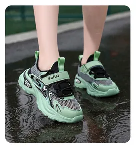 Close-up of boys' green breathable mesh running sneakers on wet asphalt
