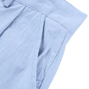 Détail macro d'un pantalon en lin bleu clair montrant la texture et la couture