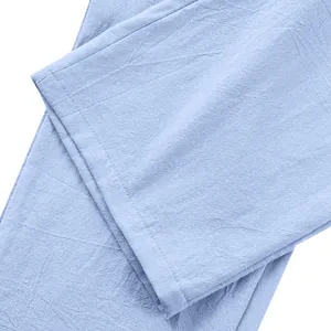 Détail d'un pantalon en lin bleu clair montrant la texture du tissu et l'ourlet soigné.