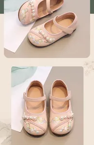 Detail showing elegant pink girls' leather flats with traditional floral embroidery and pearls
