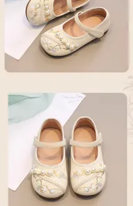 Detailed close-up view of girls' cream Mary Janes featuring floral embroidery and pearls