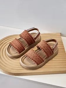 Primer plano de sandalias para niña de estilo bohemio con detalles de ganchillo en madera.