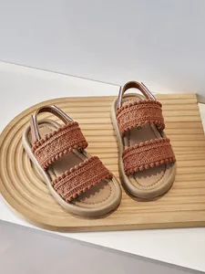 Detalle de sandalias étnicas para niña con tiras de ganchillo y suelas marrones suaves