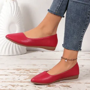 Detail view of stylish red pointed-toe flat shoes worn with blue denim jeans